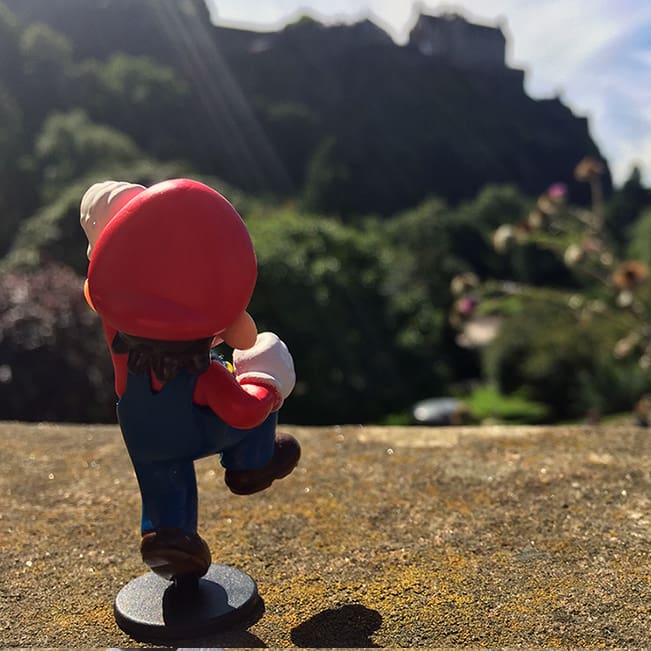 Mario throwing a fist into the air with Edinburgh Castle in the background.