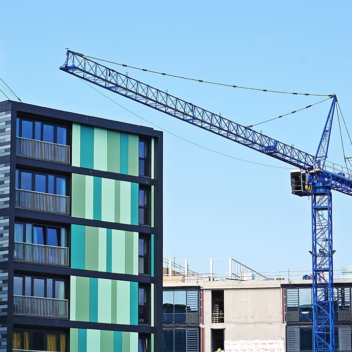 A crane against a blue sky, beside high-rise buildings