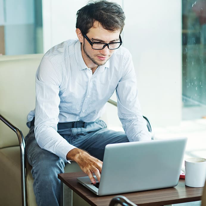 Male student at desk with laptop and cup of coffee