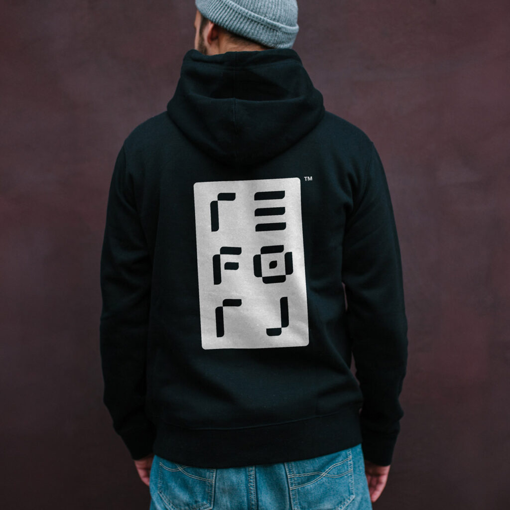 Male wearing a black hoody with the Reforj logo printed on the back in white